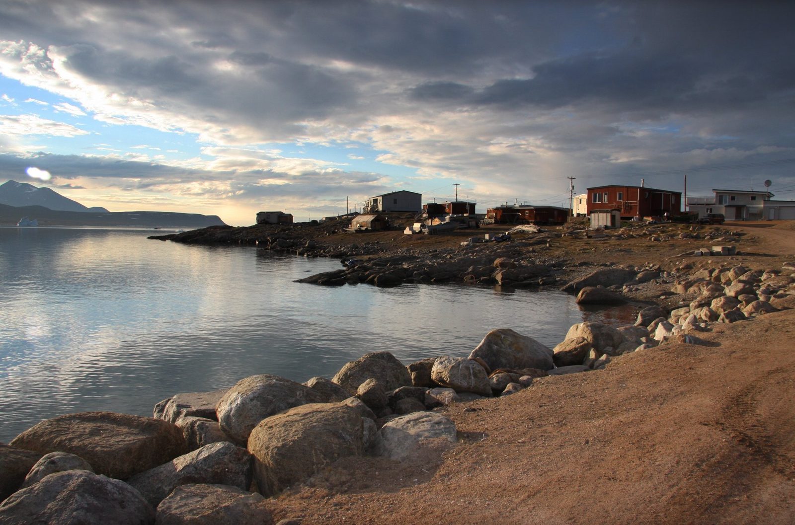 An Arctic community at the shoreline, iceberg offshore